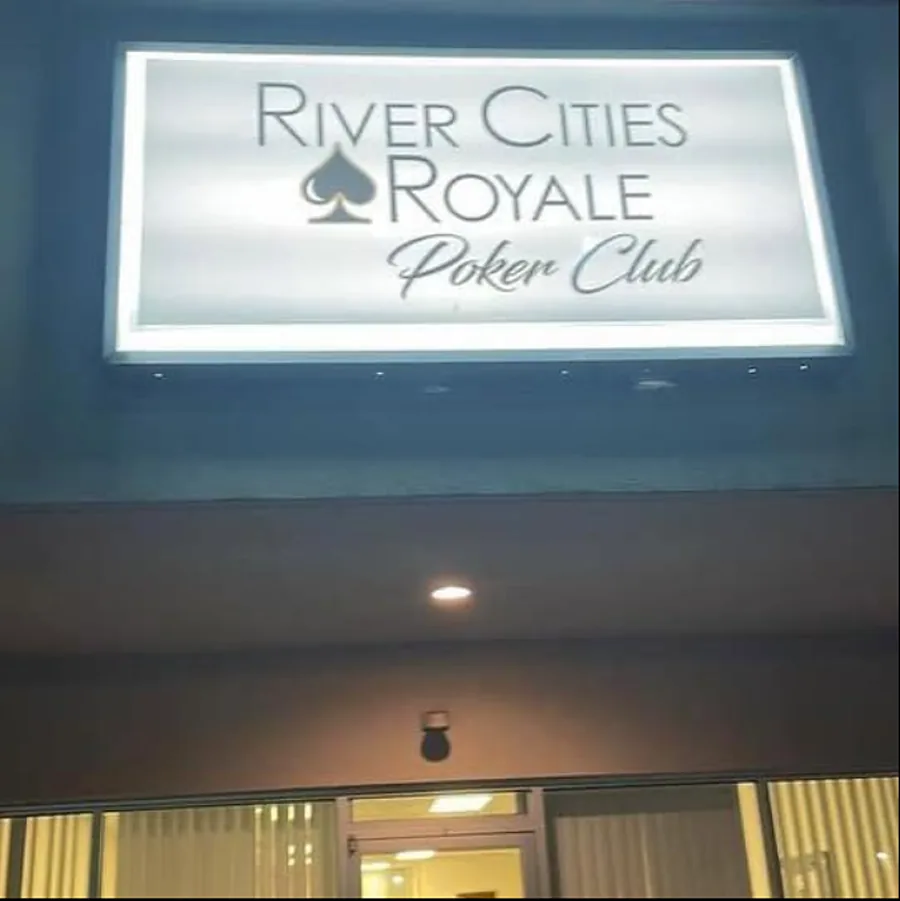 The lit River Cities Royale Poker Club sign above the front door at night