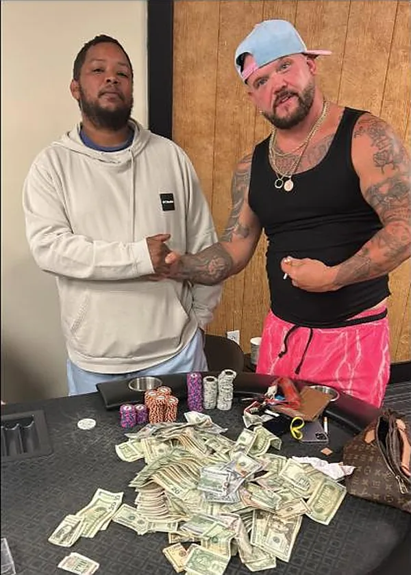 Two players behind a table covered in cash after chopping the $5,000 guarantee
